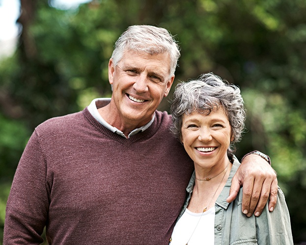 Man and woman smiling after all ceramic dental restorations