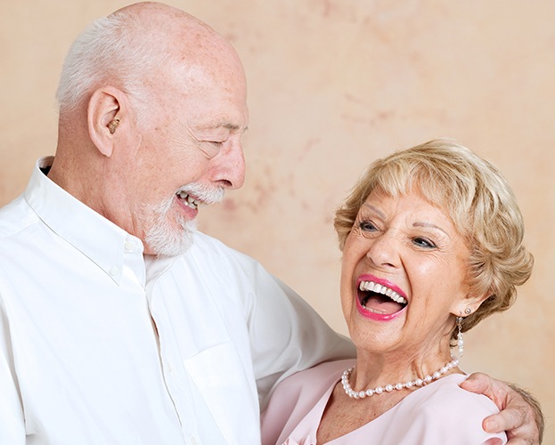 Older man and woman smiling after senior dentistry checkup