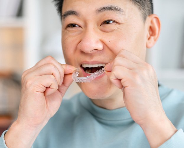 smiling man putting Invisalign in his mouth