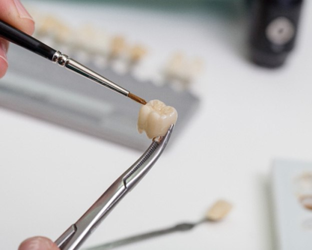 closeup of a dental crown being held with dental tools