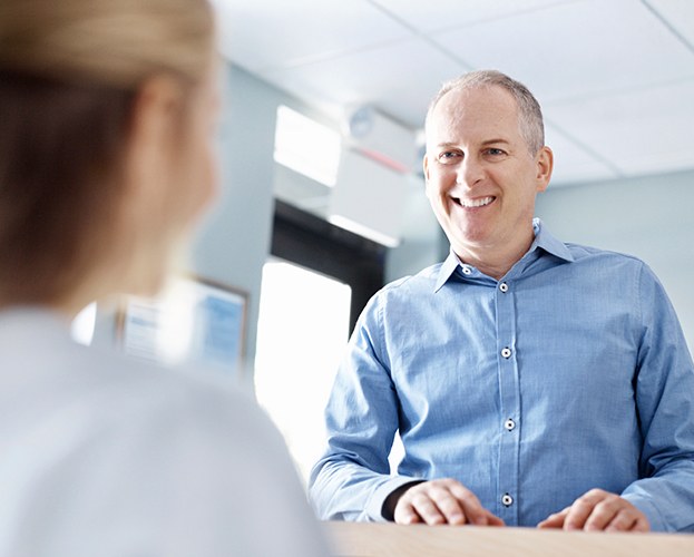 Man checking in at dental office reception desk