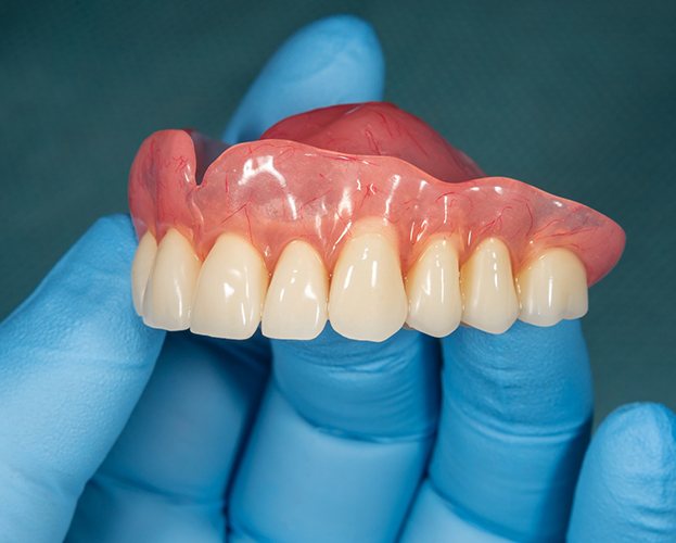 hand holding a full denture in Williamsville