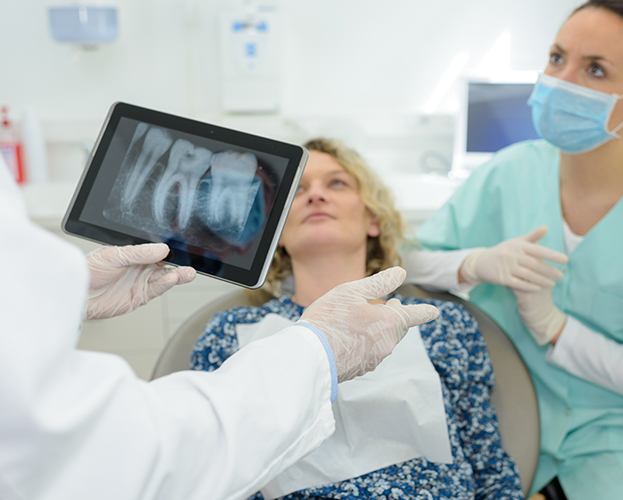 Dentist and patient looking at digital x-rays on tablet computer