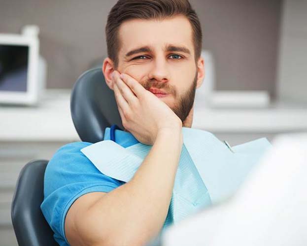 Man in dental chair wondering about the cost of dental emergencies in Williamsville