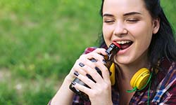 Woman opening bottle with teeth will visit Williamsville emergency dentist soon