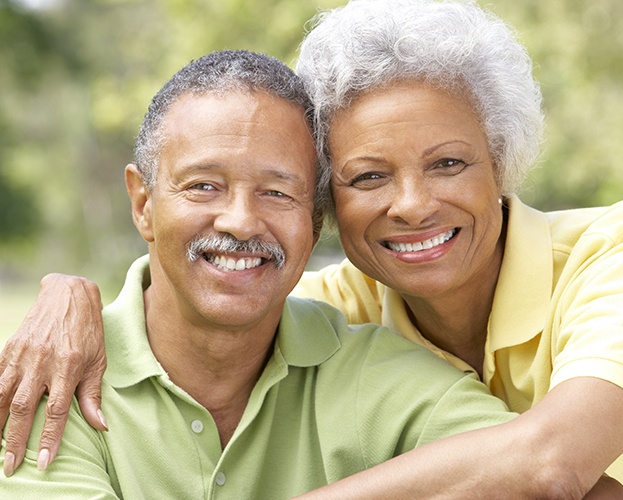 Older man and woman smiling after denture placement