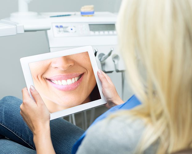 Woman looking at virtual smile design on tablet computer