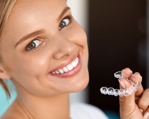 Woman holding Invisalign clear braces tray
