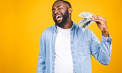 Man in denim jacket fanning himself with money