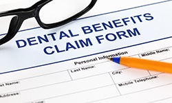 Glasses and pen on top of dental benefits claim form