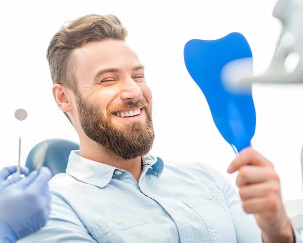 happy patient looking at his implant dentures in Williamsville