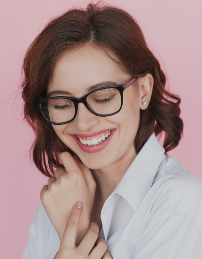 Young woman with glasses smiling against pink background