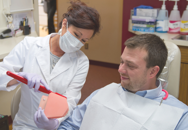 Williamsville dental team member showing patient how to brush teeth