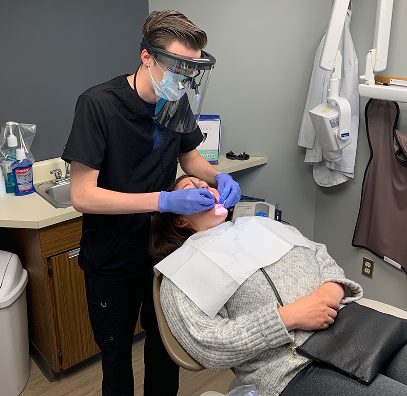 Dental team member in Williamsville checking patient's mouth