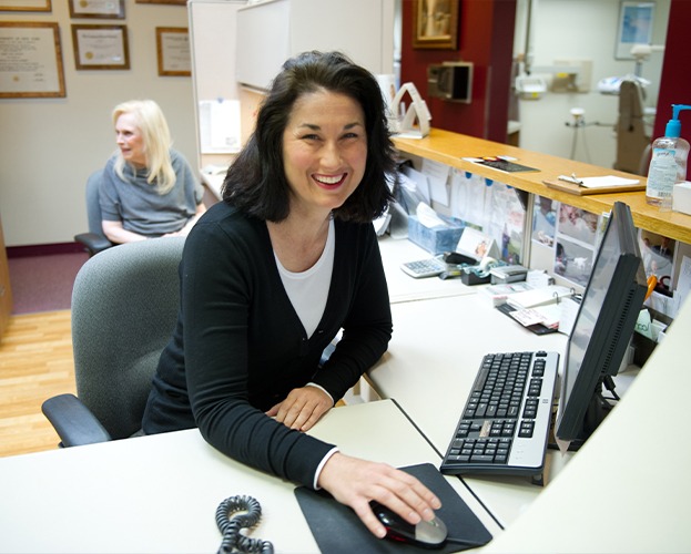 Smiling dental team member at reception desk