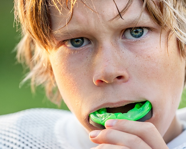 Teen placing athletic mouthguard