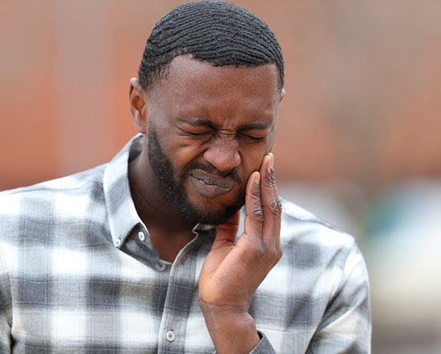 man holding his face and needing root canal therapy