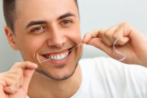 man smiling flossing keeping up with your oral hygiene through the quarantine