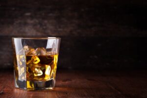 glass of alcohol and ice with dark background